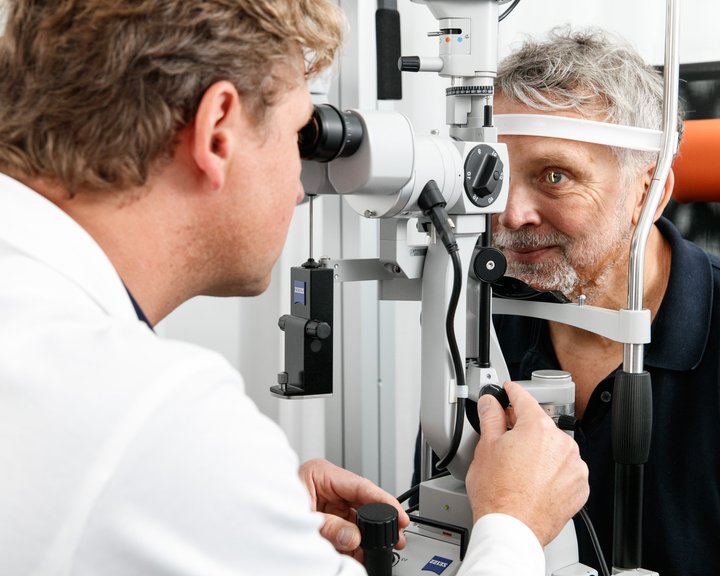 Ein Augenarzt führt an einer Spaltlampe eine detaillierte Untersuchung des Augenhintergrunds bei einem Patienten durch.