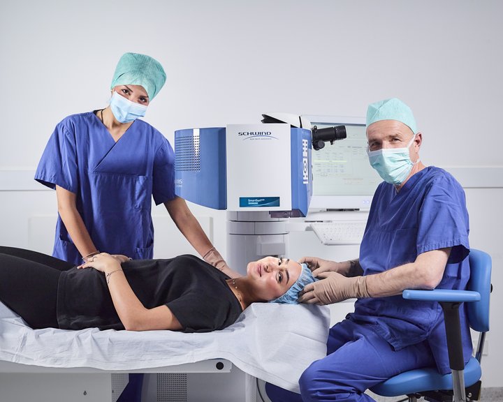 Ein chirurgisches Team bereitet eine Patientin unter einem SCHWIND-Augenlasergerät auf eine Laser-OP vor.