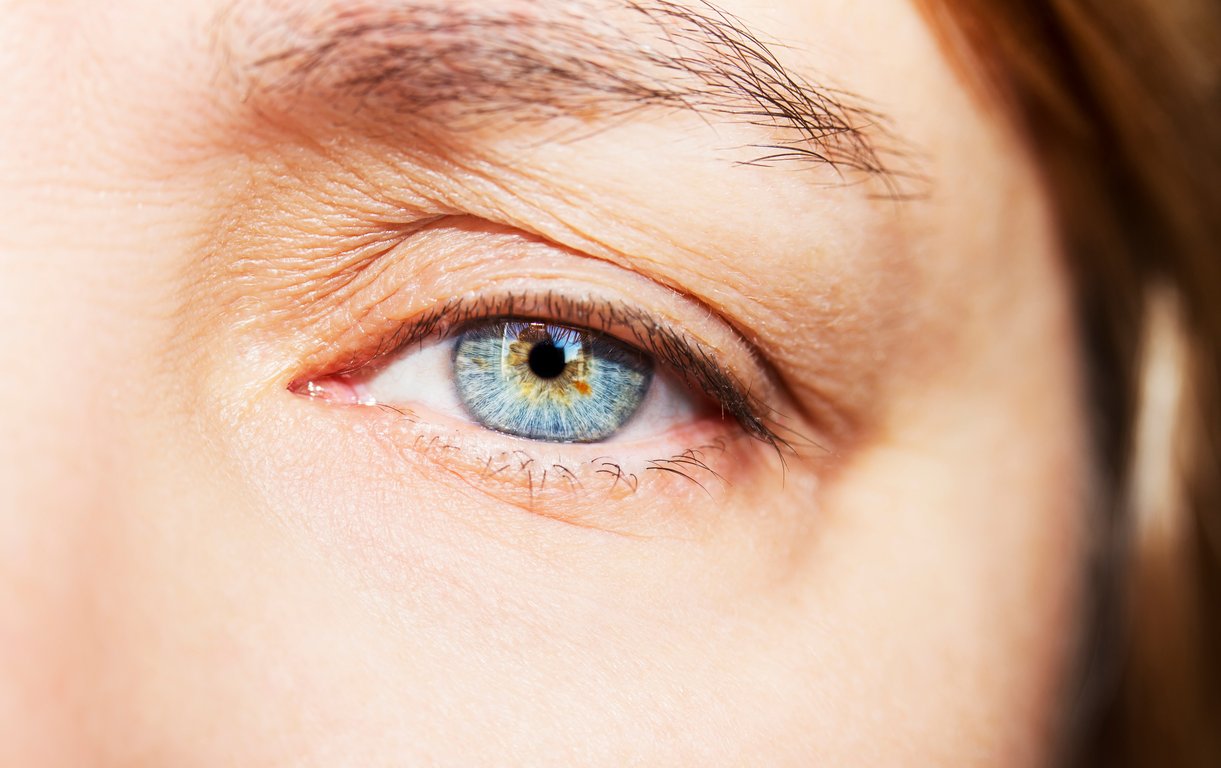 Detailreiche Nahaufnahme eines hellblauen menschlichen Auges mit feinen Strukturen in der Iris und umgebender Hautpartie.